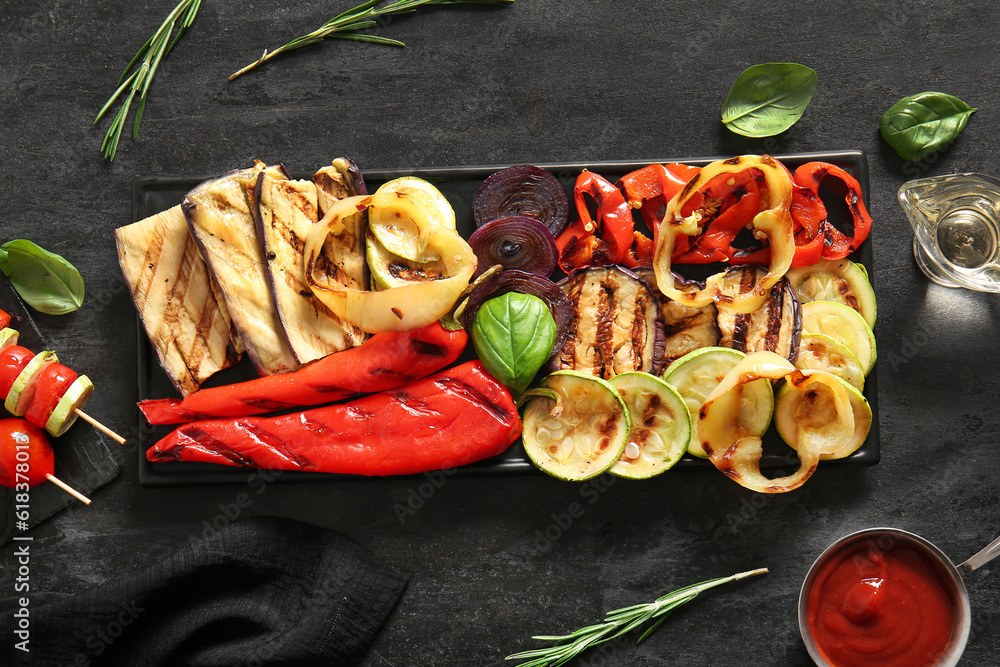 Plate with tasty grilled vegetables on black background