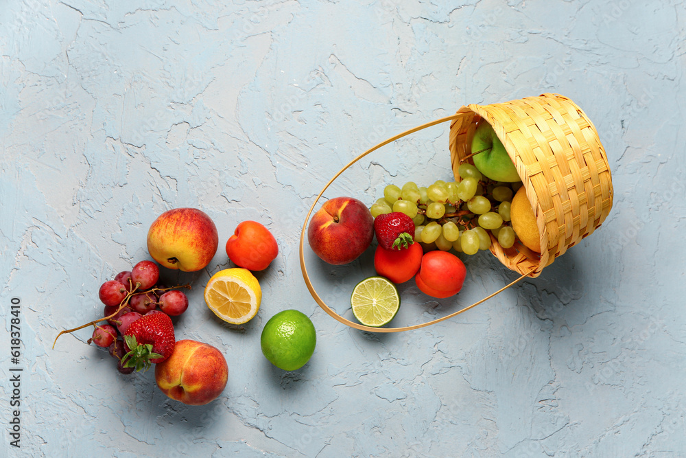 Wicker basket with different fresh fruits on blue background