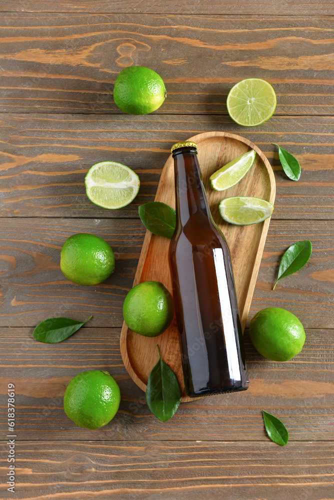 Bottle of cold beer with lime on wooden background