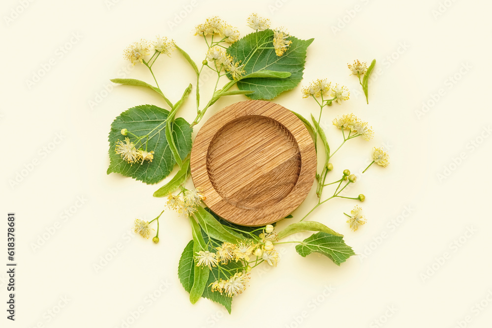 Composition with wooden plate, fresh linden flowers and leaves on color background