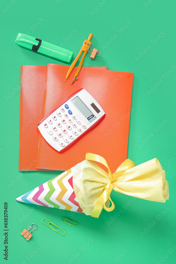 Yellow school cone with different stationery on green background