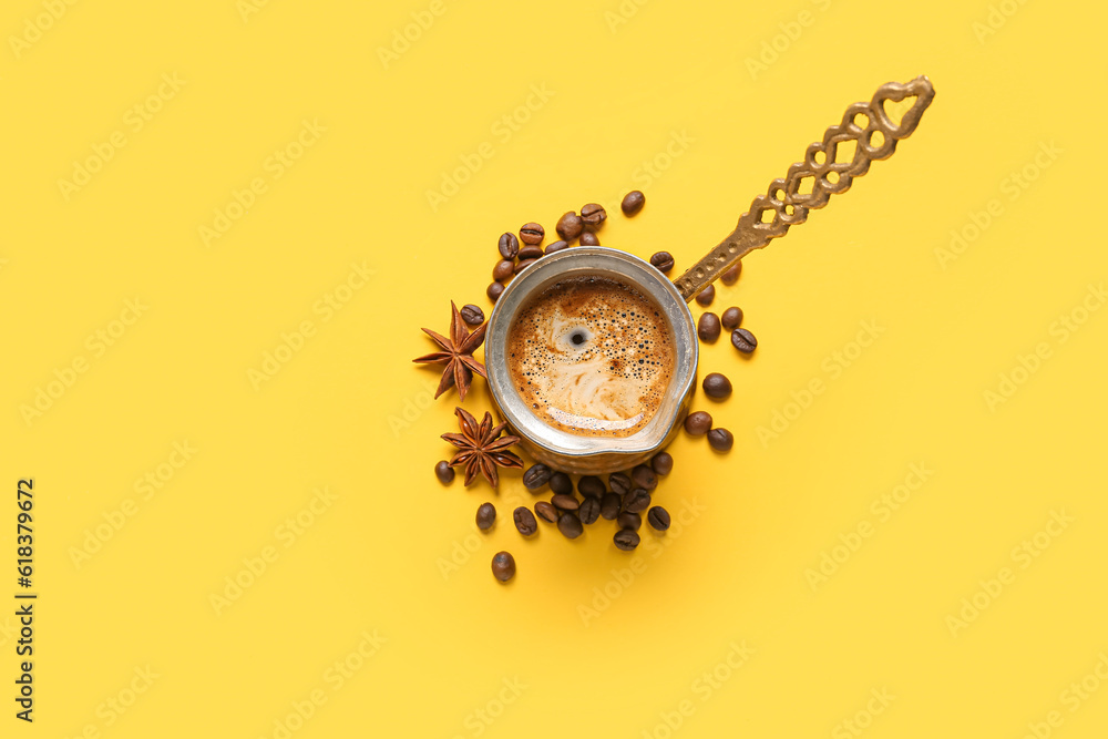 Cezve with coffee, beans and star anise on yellow background