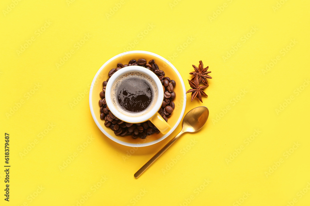 Cup of coffee served with beans and star anise on yellow background