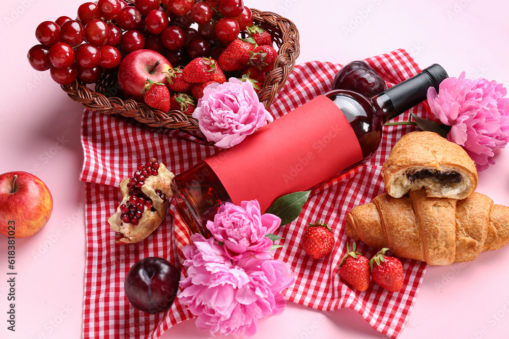 Composition with tasty food for picnic, bottle of wine and peony flowers on pink background, closeup