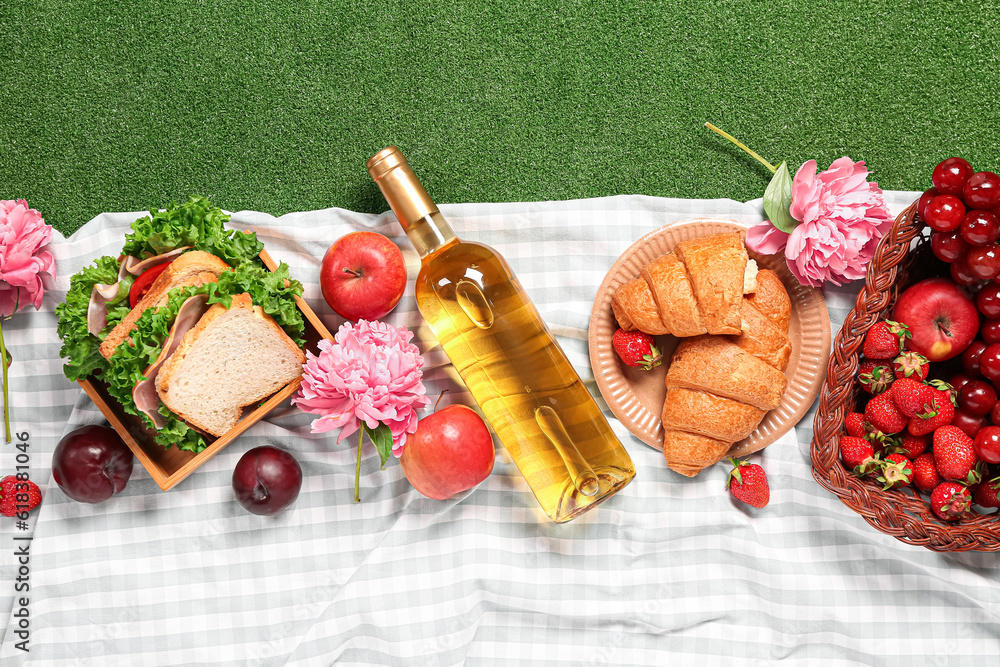 Composition with tasty food for picnic, wine and peony flowers on green background