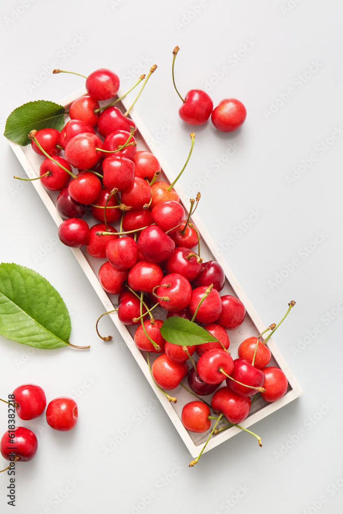 Tray with sweet cherries on white background