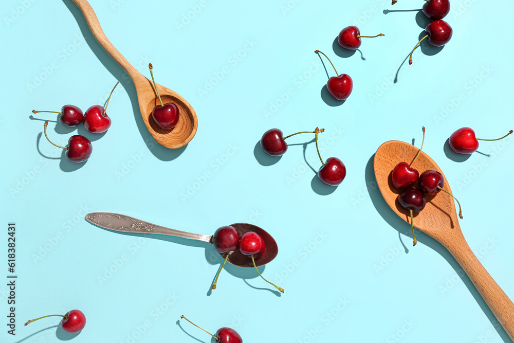 Spoons with sweet cherries on blue background