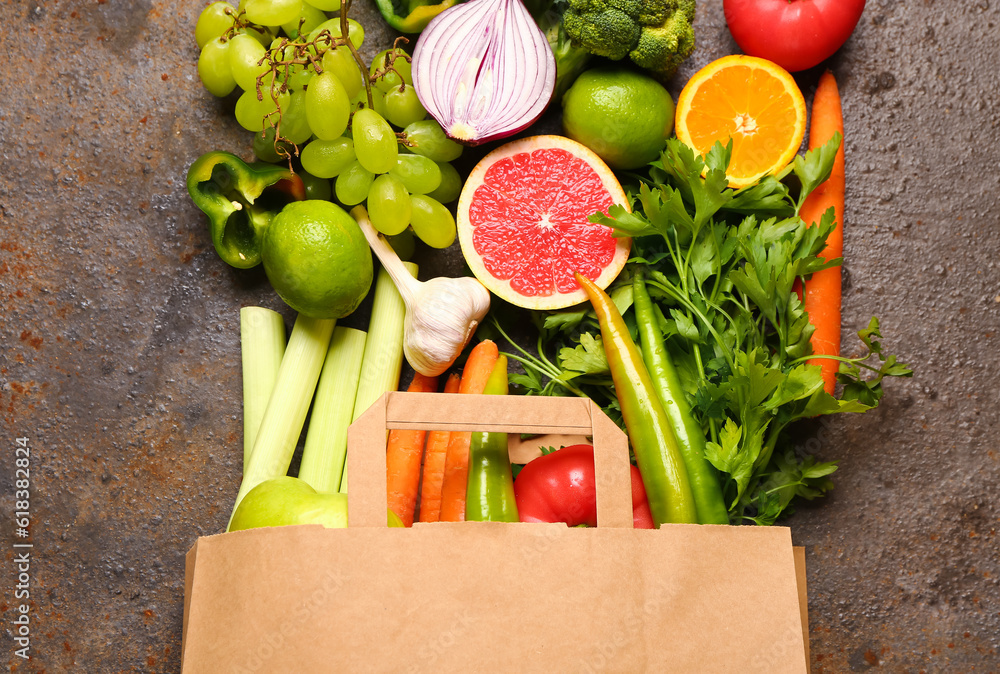 Paper bag with different fresh fruits and vegetables on dark background