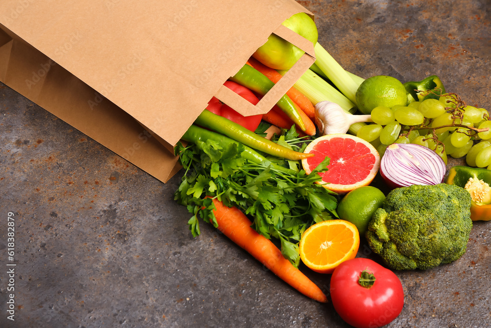 Paper bag with different fresh fruits and vegetables on dark background