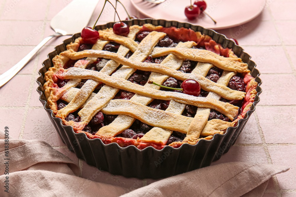 Baking dish with tasty cherry pie on pink tile background