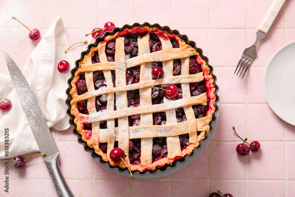 Baking dish with tasty cherry pie on pink tile background