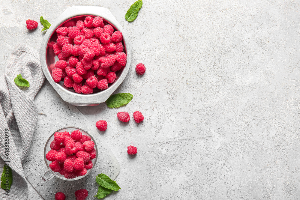 Metal plate and glass cup with fresh raspberries on grey background