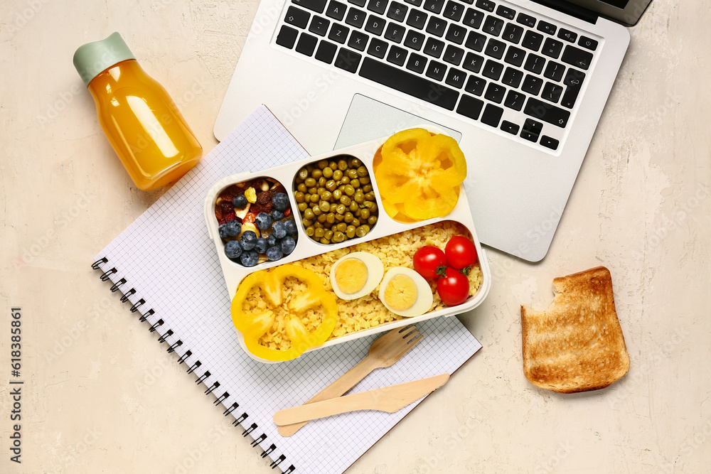 Laptop, bottle of juice and lunchbox with tasty food on white background