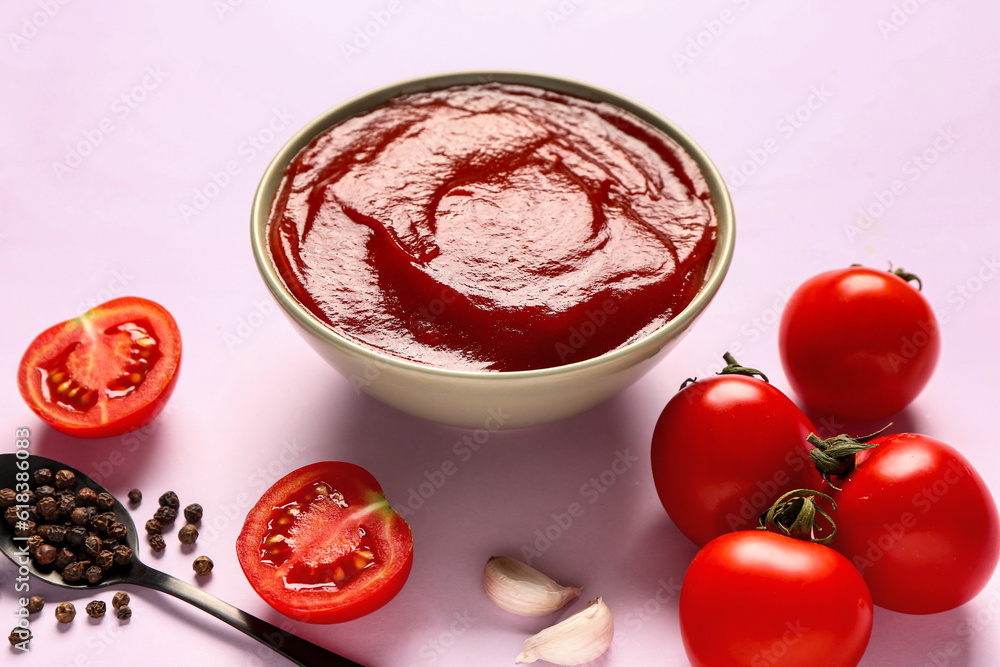 Bowl with tomato paste and fresh vegetables on lilac background