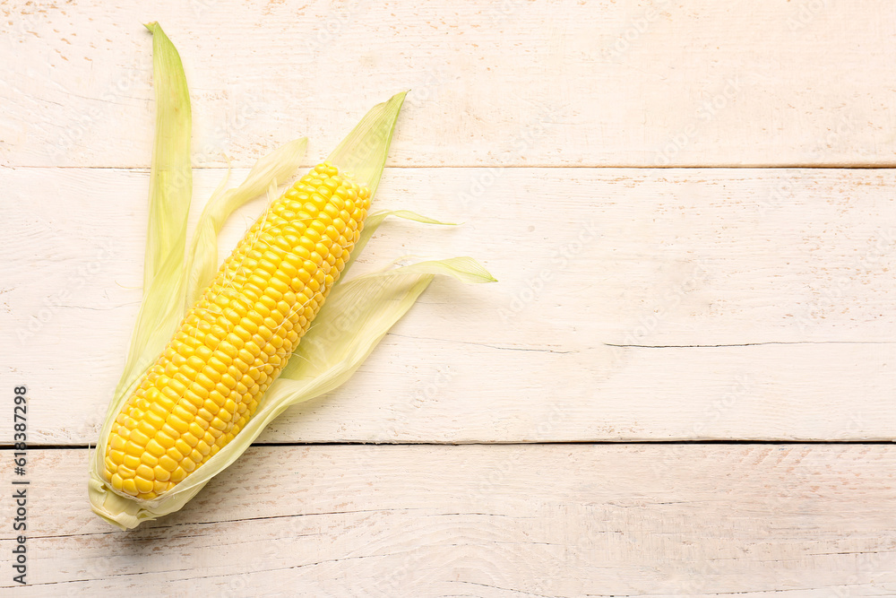 Fresh corn cob on white wooden background