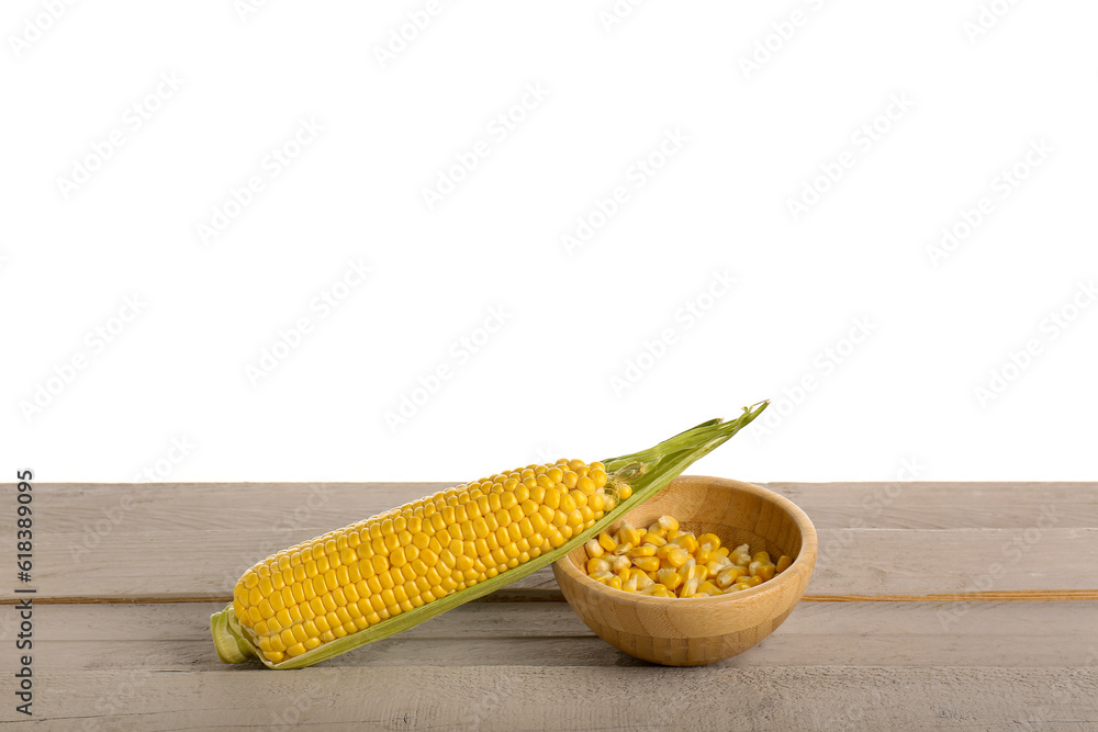 Fresh corn cob and bowl with seeds on grey wooden table against white background