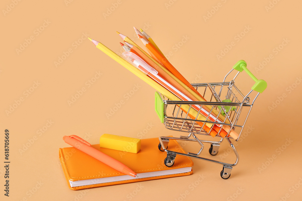 Shopping cart with different stationery on color background