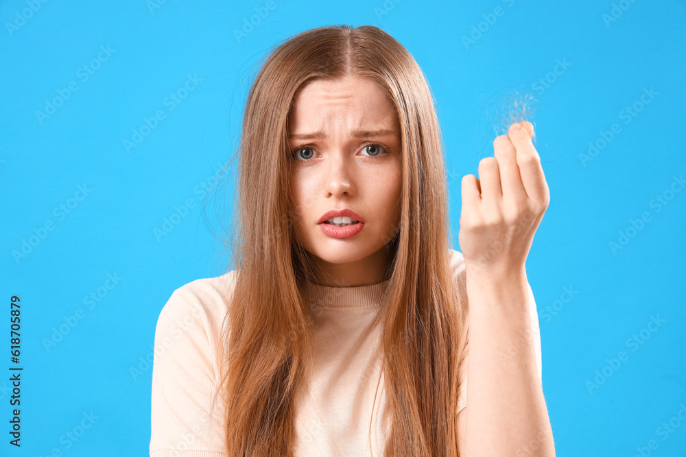 Worried young woman with hair loss problem on blue background