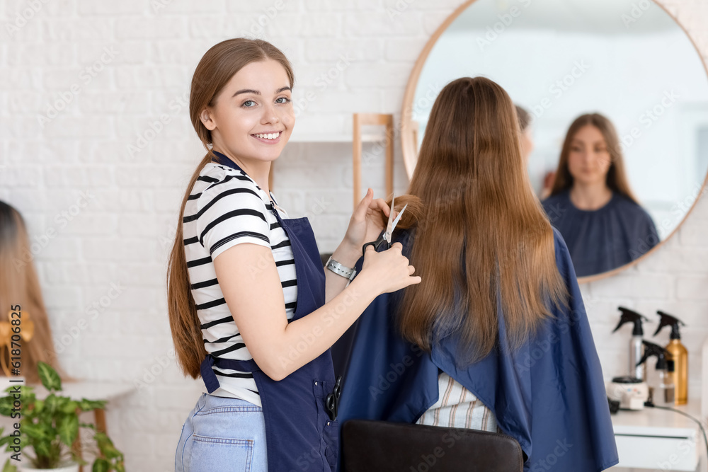 Female hairdresser cutting young womans hair in beauty salon