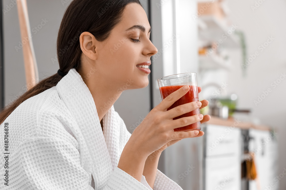 Young woman with glass of vegetable juice in kitchen, closeup