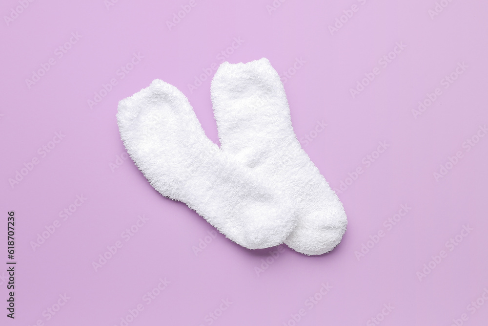 Pair of warm white socks on lilac background