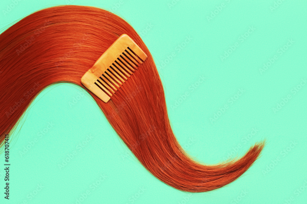 Beautiful ginger hair with comb on color background