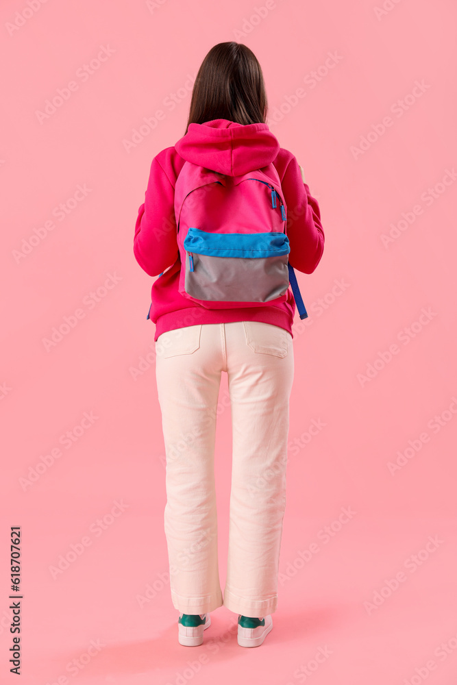 Female student with backpack on pink background, back view