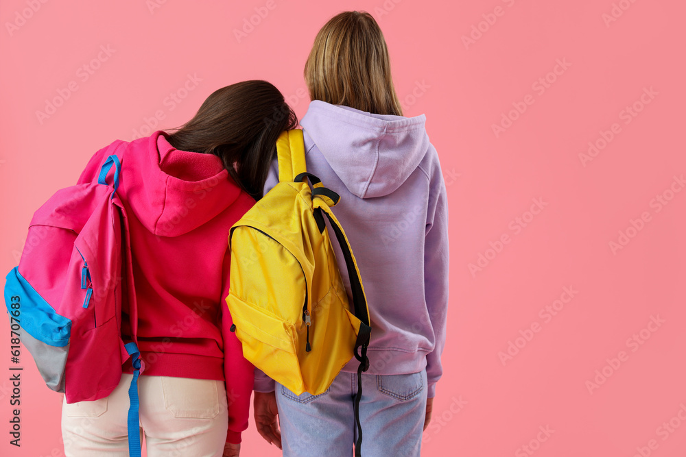 Female students with backpacks on pink background, back view