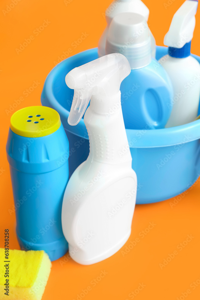 Bowl with different cleaning supplies on orange background, closeup