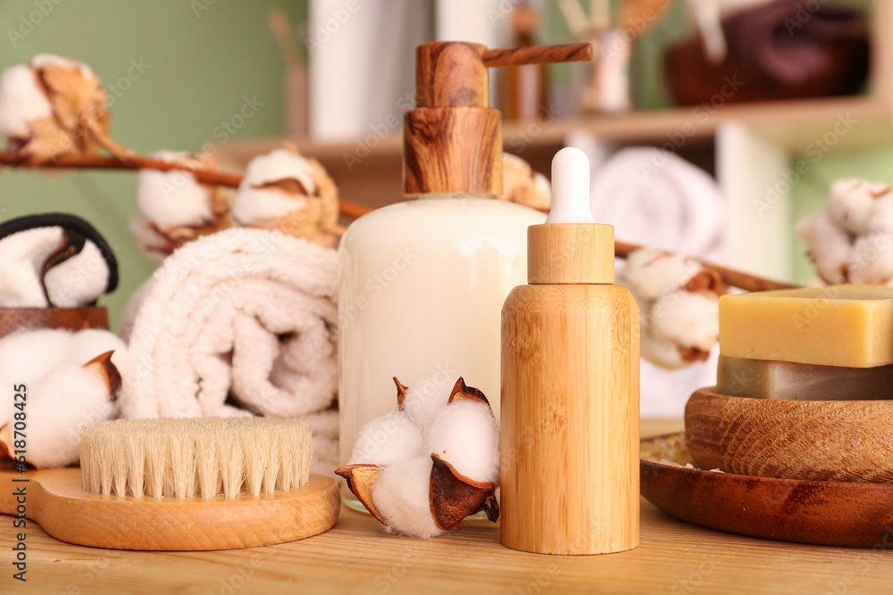 Set of cosmetic products, bath supplies and cotton flowers on wooden table, closeup