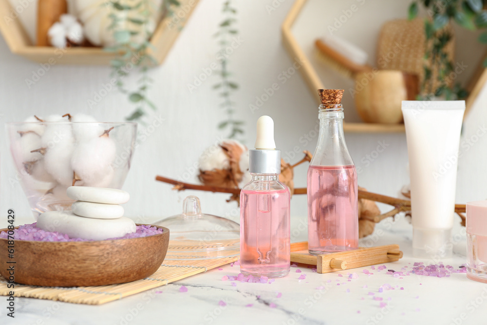 Set of cosmetic products and cotton flowers on light table in room