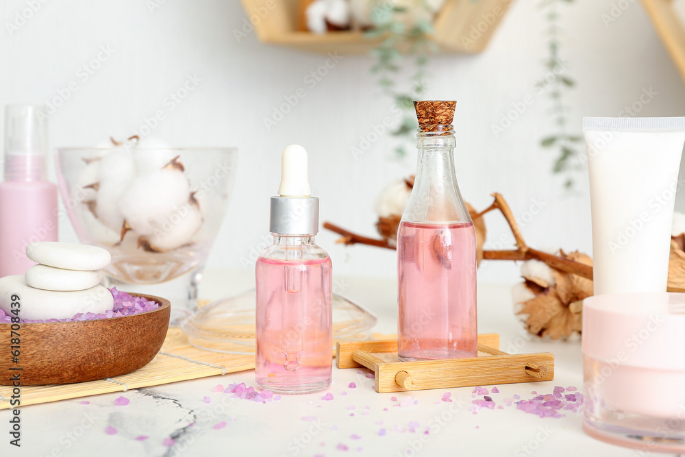 Set of cosmetic products and cotton flowers on light table in room