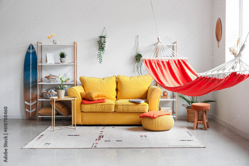 Interior of stylish living room with red hammock, yellow sofa and coffee table