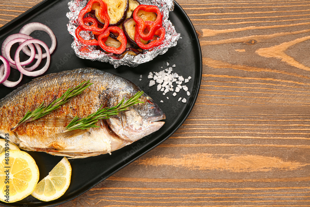 Tray with tasty grilled dorado fish on wooden background