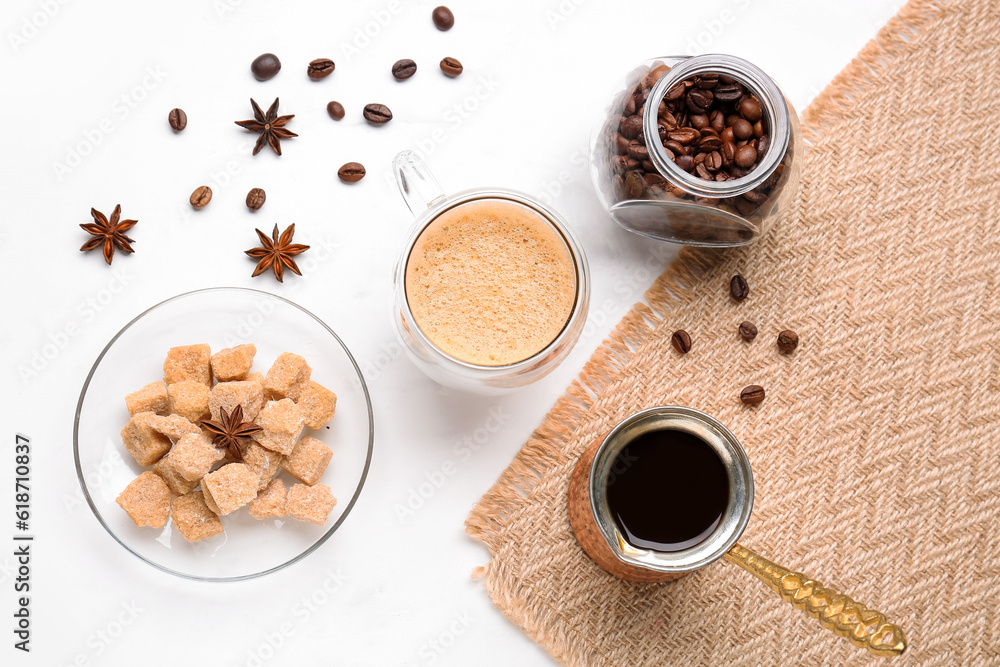 Glass cup of hot espresso and jar with coffee beans on white background