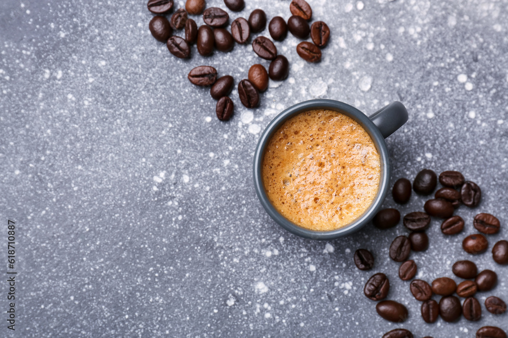 Cup of hot espresso and coffee beans on grey background