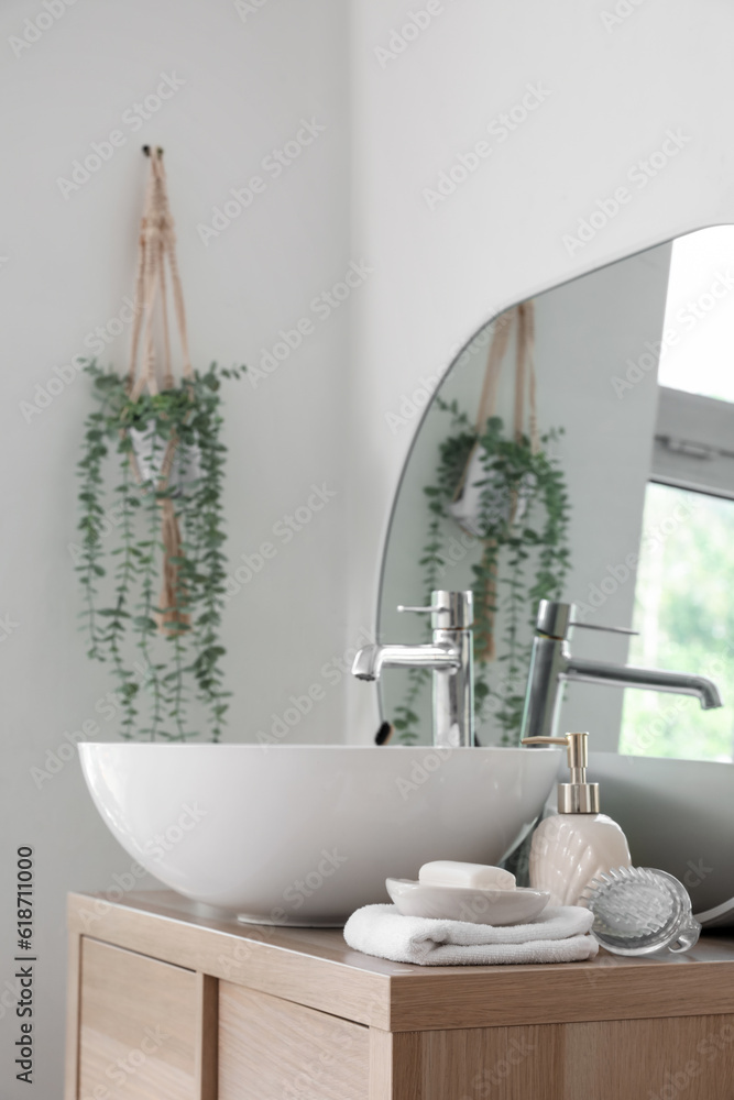 Sink bowl, soap bar and dispenser on wooden cabinet in bathroom