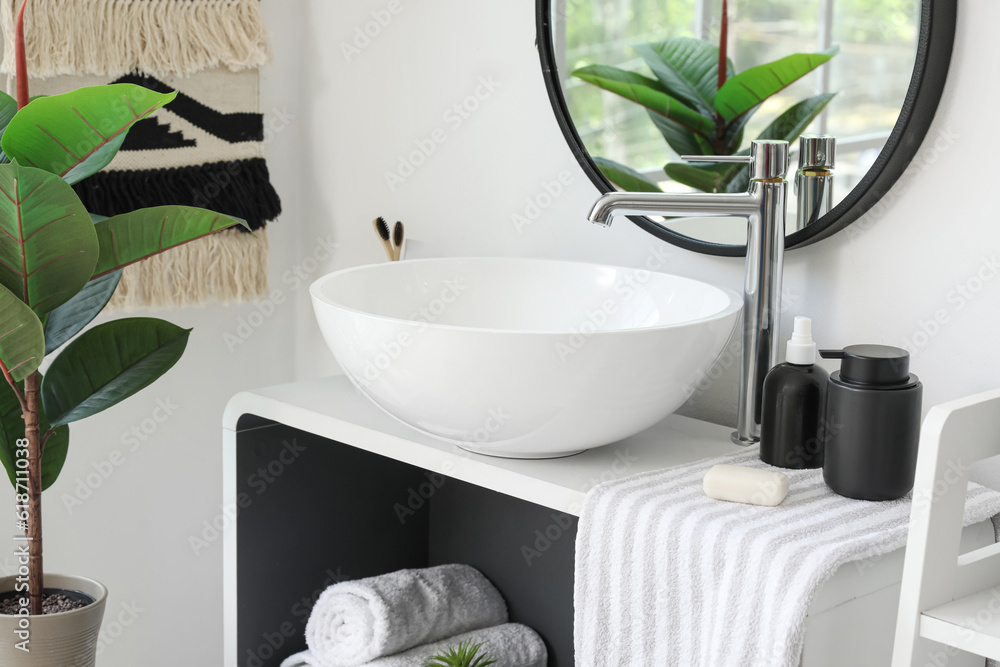 Sink bowl, soap bar, towel and bath accessories on shelving unit in bathroom