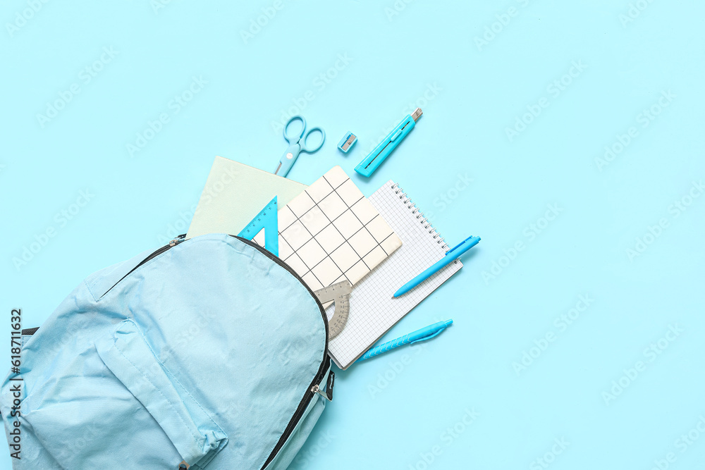 School backpack with different stationery on blue background