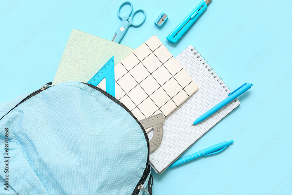 School backpack with different stationery on blue background