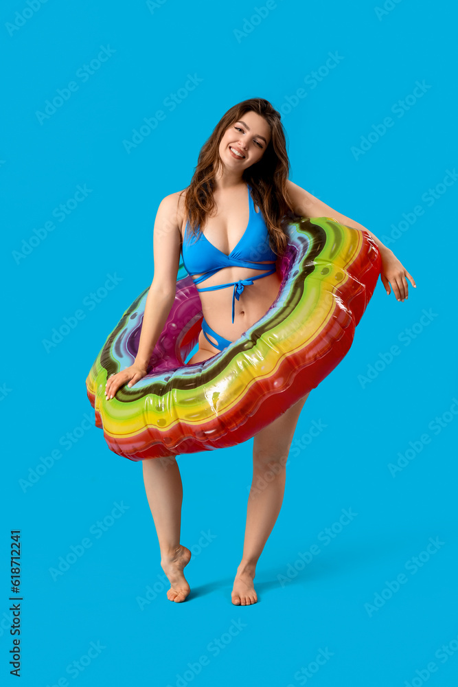 Young woman with swim ring on blue background