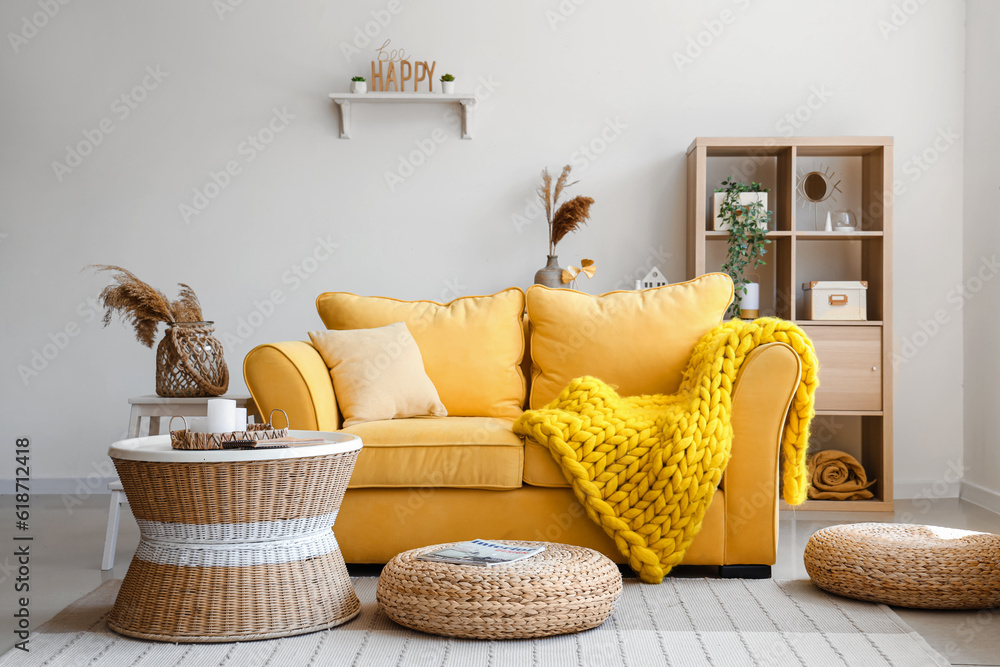 Interior of light living room with stylish yellow sofa, coffee table and wicker poufs