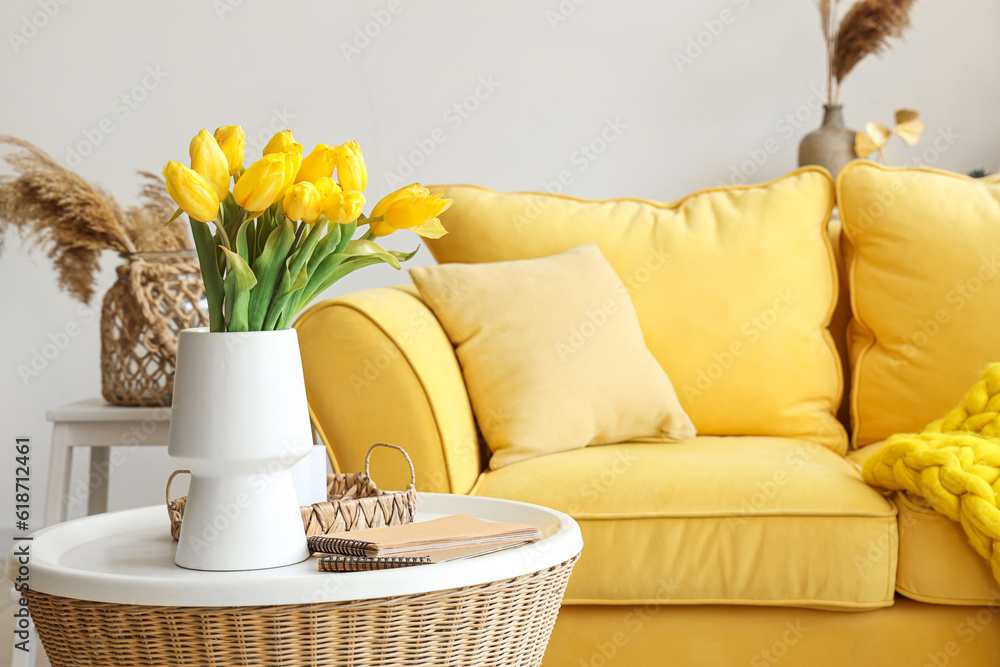 Vase with blooming tulip flowers on coffee table in interior of living room