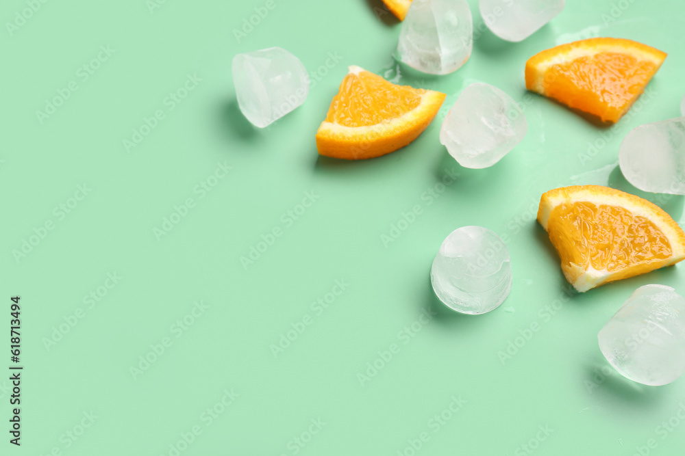 Orange pieces with ice cubes on turquoise background