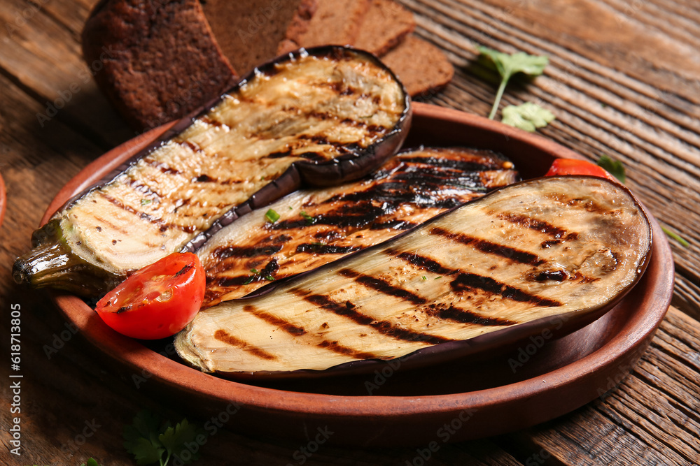 Plate with delicious grilled eggplants and tomatoes on wooden background, closeup