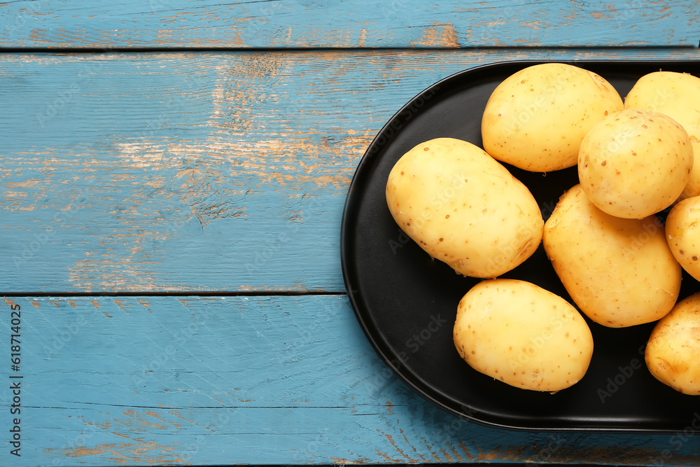 Tray with raw baby potatoes on blue wooden background