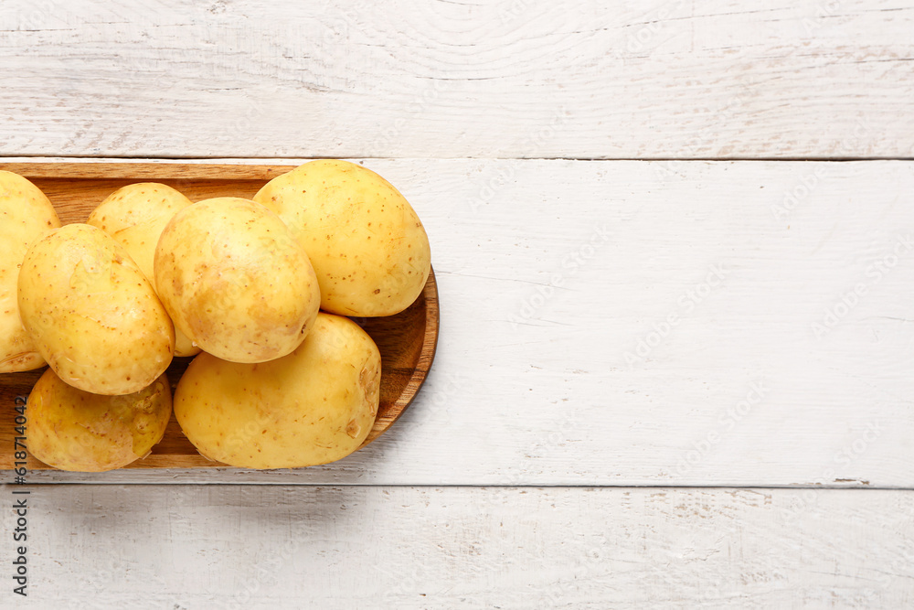 Tray with raw baby potatoes on white wooden background