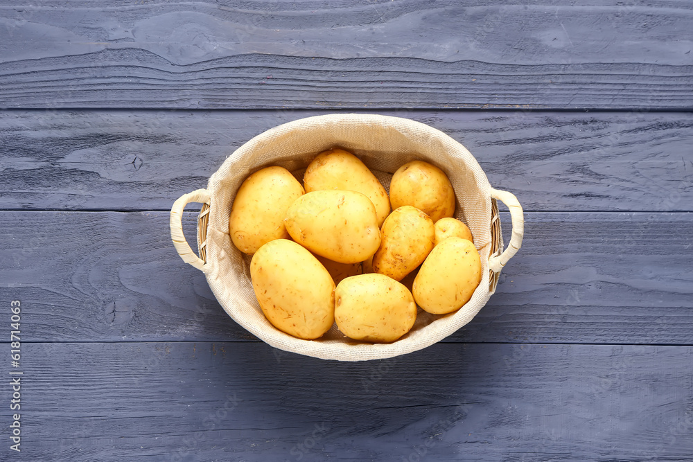 Wicker basket with raw baby potatoes on blue wooden background