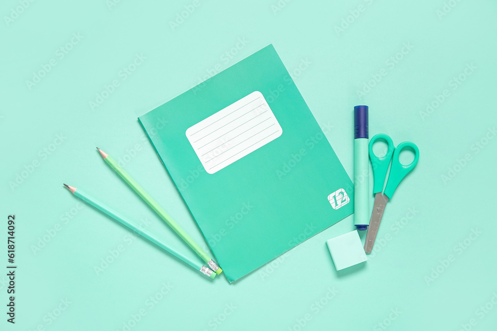 Notebook with different stationery on turquoise background