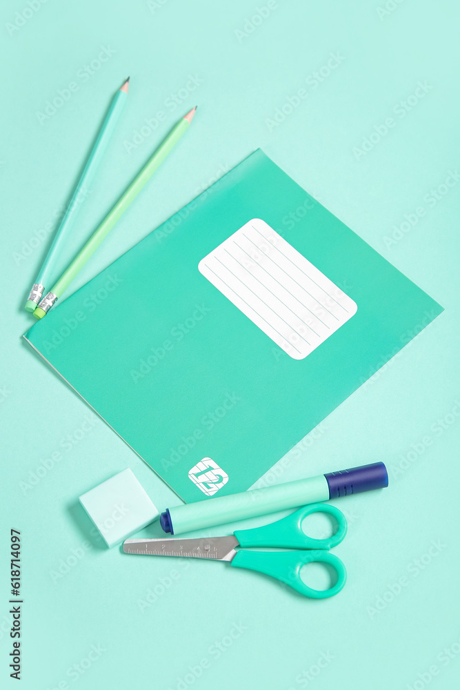 Notebook with different stationery on turquoise background